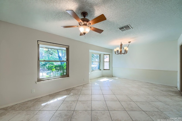 unfurnished room with light tile patterned floors, ceiling fan with notable chandelier, visible vents, and a textured ceiling