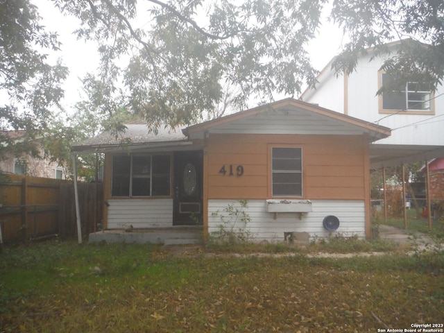 view of front of home with an attached carport and fence