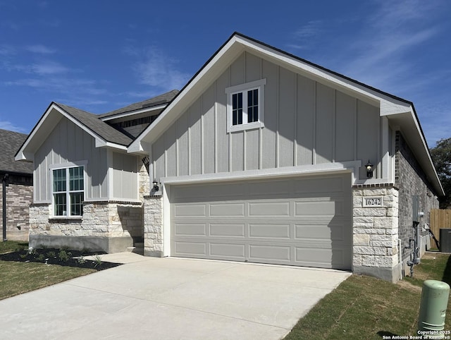 view of front of home with stone siding, an attached garage, board and batten siding, and driveway