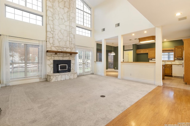 unfurnished living room featuring visible vents, light colored carpet, and a stone fireplace