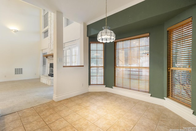 unfurnished dining area featuring tile patterned floors, visible vents, ornamental molding, carpet flooring, and baseboards