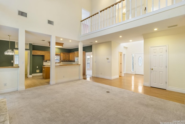 unfurnished living room with a chandelier, visible vents, light colored carpet, and baseboards