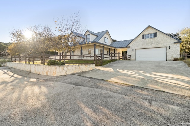 view of front of home with a standing seam roof, concrete driveway, stone siding, a fenced front yard, and metal roof