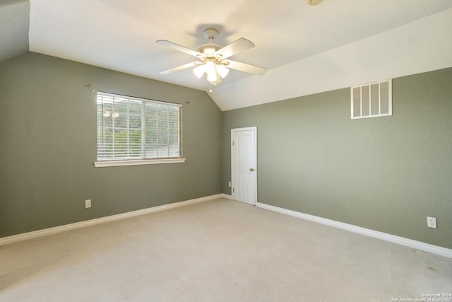 empty room with visible vents, a ceiling fan, baseboards, lofted ceiling, and light colored carpet