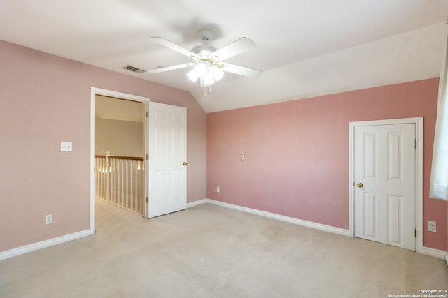 unfurnished bedroom featuring light carpet, visible vents, baseboards, and vaulted ceiling