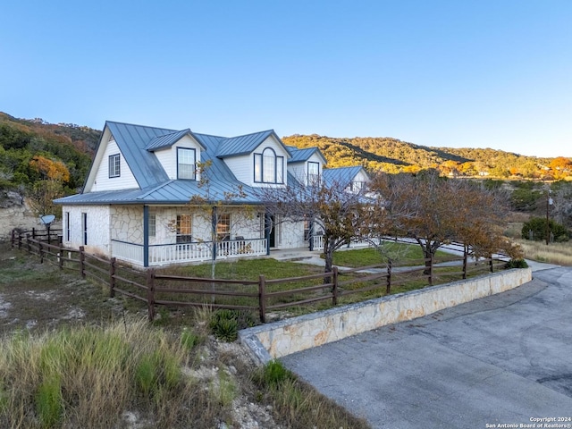 view of front of property with fence, metal roof, stone siding, a mountain view, and a standing seam roof