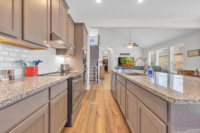 kitchen with a sink, stainless steel appliances, vaulted ceiling, under cabinet range hood, and open floor plan