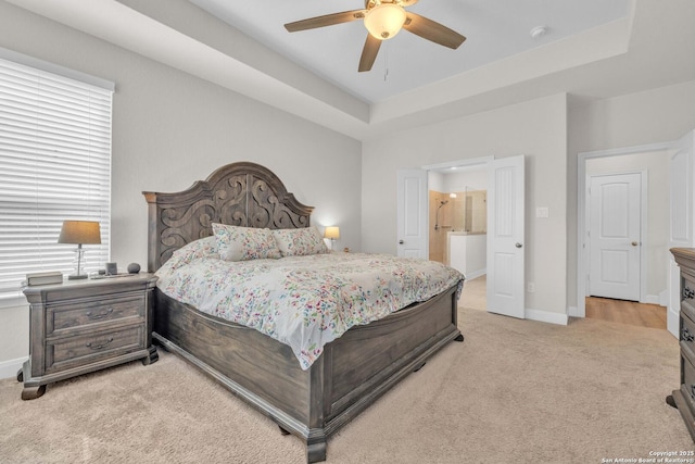 bedroom with a tray ceiling, baseboards, and light colored carpet