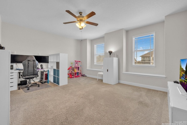 office area featuring baseboards, light carpet, and ceiling fan