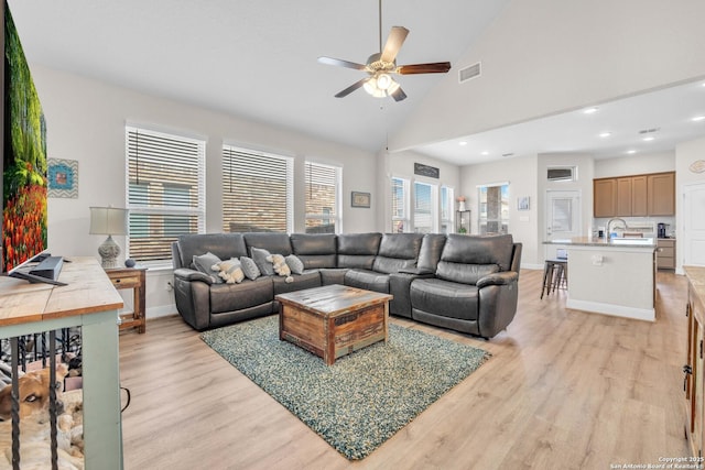 living room featuring light wood-type flooring, visible vents, high vaulted ceiling, baseboards, and ceiling fan