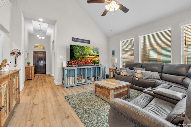 living room featuring ceiling fan with notable chandelier, baseboards, light wood finished floors, and high vaulted ceiling