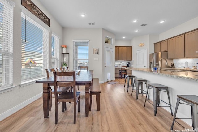 dining area featuring visible vents, light wood-style flooring, and baseboards