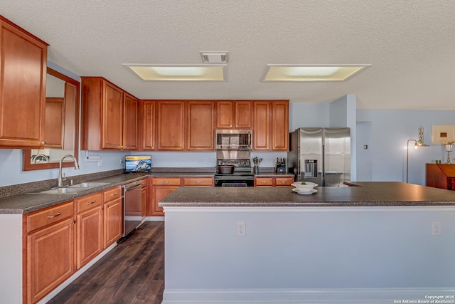 kitchen with visible vents, a sink, dark countertops, dark wood-style floors, and appliances with stainless steel finishes