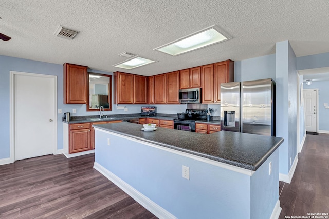 kitchen with dark wood-style flooring, dark countertops, visible vents, and appliances with stainless steel finishes