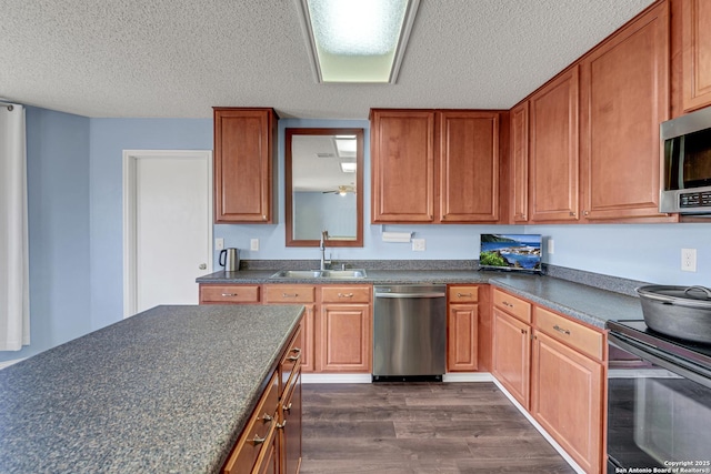 kitchen featuring a sink, stainless steel appliances, dark countertops, and dark wood-style floors