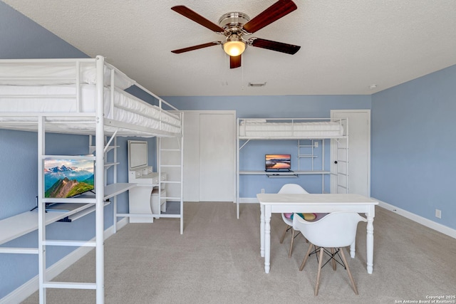 carpeted bedroom with visible vents, a textured ceiling, baseboards, and a ceiling fan