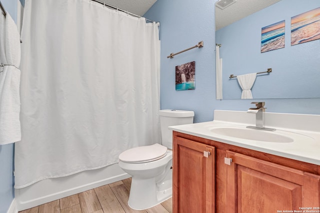 full bathroom featuring visible vents, toilet, vanity, wood finished floors, and a textured ceiling