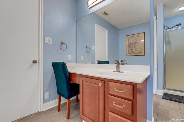 full bathroom with wood finish floors, visible vents, a stall shower, and vanity