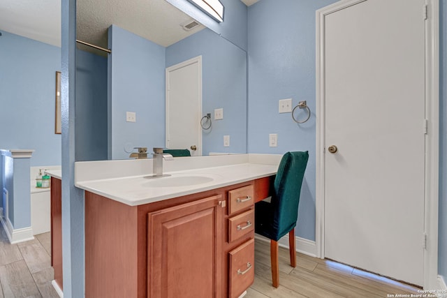 bathroom featuring visible vents, baseboards, wood finished floors, and vanity