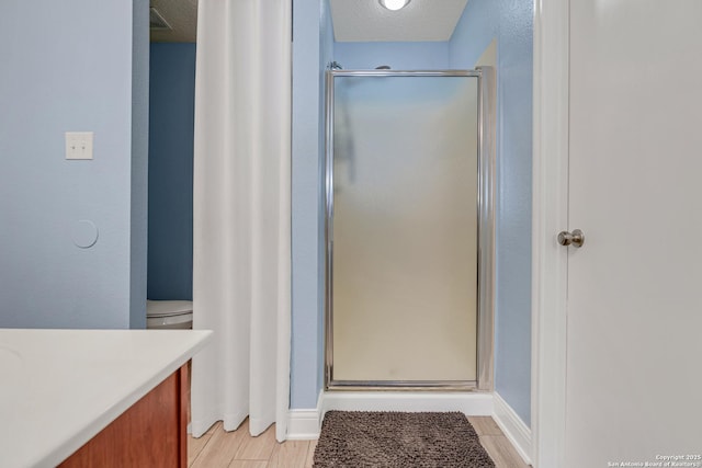 full bathroom with a stall shower, a textured ceiling, vanity, and wood finished floors