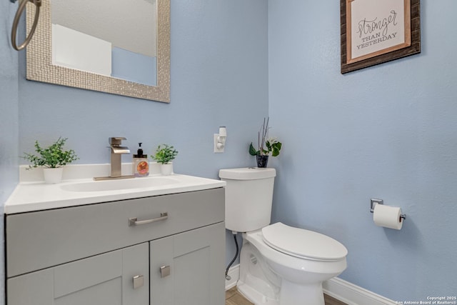 bathroom featuring vanity, toilet, and baseboards