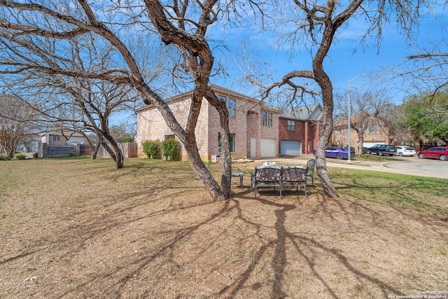 view of front facade featuring fence, a front lawn, concrete driveway, a garage, and brick siding