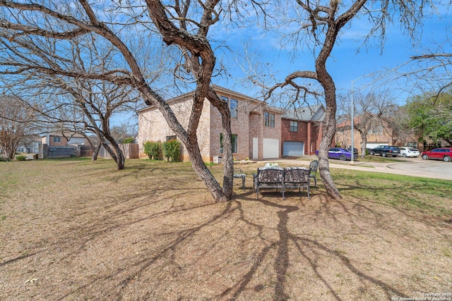 view of front of home with fence, driveway, a front lawn, a garage, and brick siding