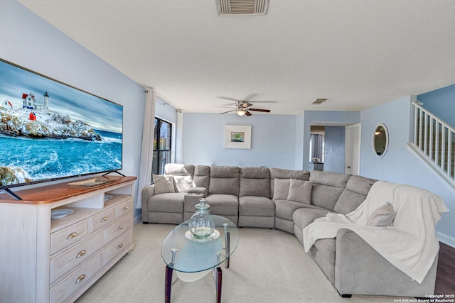 living room with visible vents, a textured ceiling, stairs, and a ceiling fan