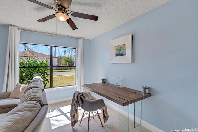 carpeted office space featuring ceiling fan, baseboards, and a textured ceiling