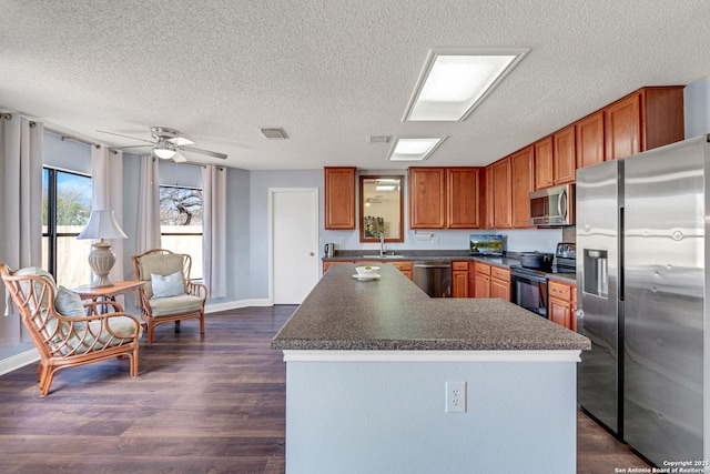 kitchen featuring visible vents, dark wood finished floors, a sink, appliances with stainless steel finishes, and dark countertops