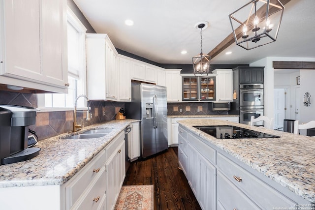 kitchen featuring dark wood finished floors, a sink, white cabinets, appliances with stainless steel finishes, and backsplash