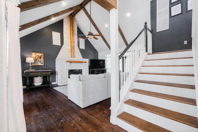 living area featuring stairway, beam ceiling, hardwood / wood-style floors, and a fireplace