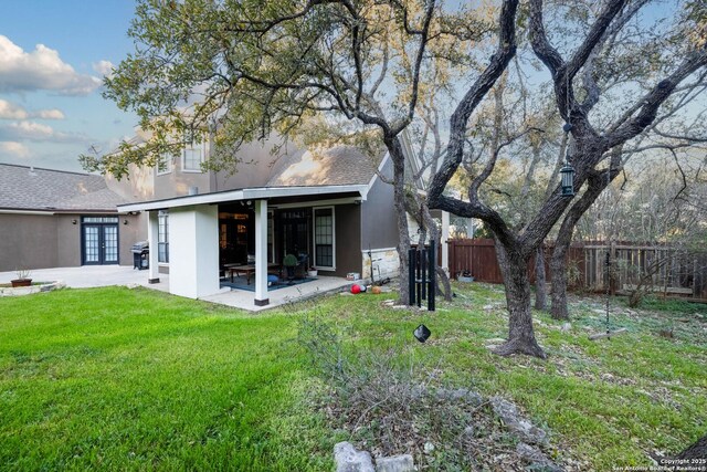 rear view of property featuring french doors, a patio area, stucco siding, and fence