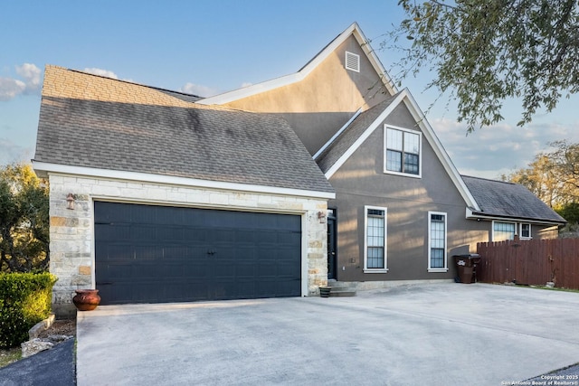 view of front of property with fence, driveway, and a shingled roof