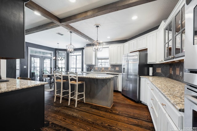 kitchen with stainless steel appliances, beam ceiling, dark wood-type flooring, and visible vents