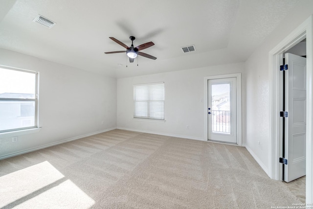 spare room with visible vents, baseboards, light colored carpet, and a ceiling fan