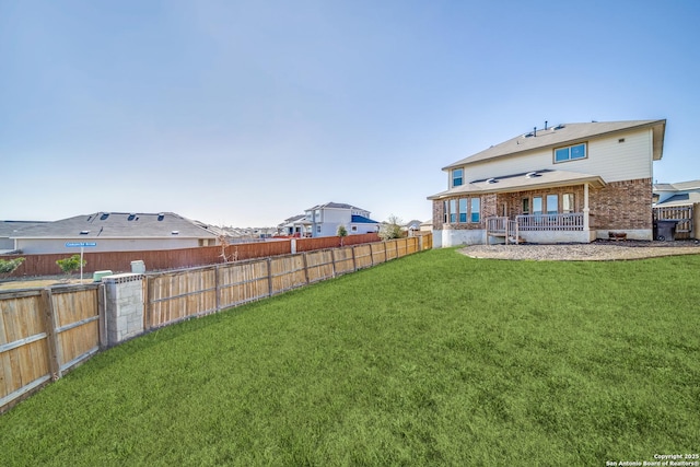 rear view of house with a lawn, brick siding, and a fenced backyard