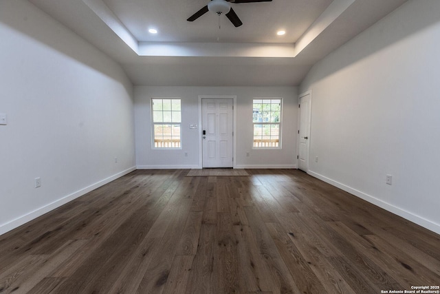 interior space featuring dark wood-type flooring, ceiling fan, baseboards, recessed lighting, and a raised ceiling