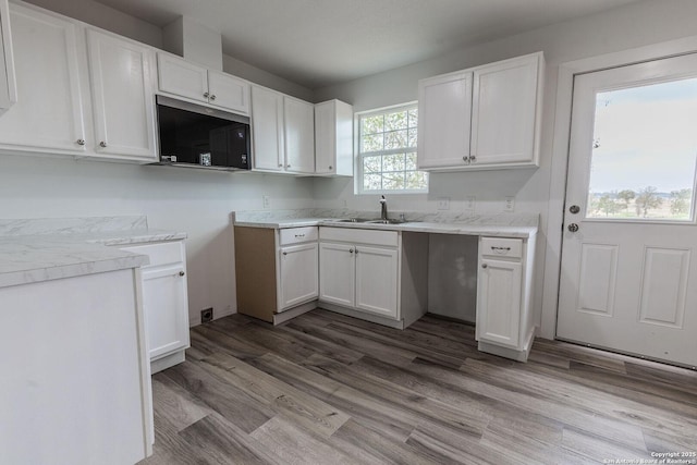 kitchen featuring a sink, wood finished floors, and white cabinets