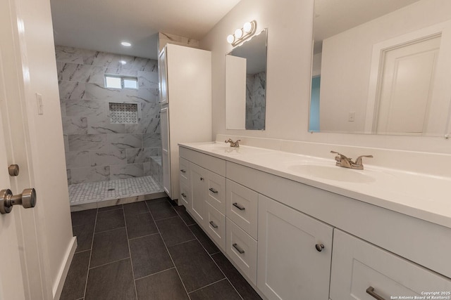 bathroom featuring double vanity, a tile shower, and a sink