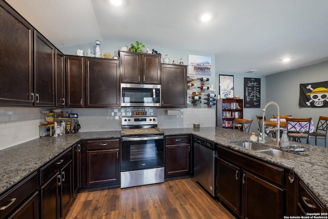 kitchen with dark wood-style flooring, a sink, dark brown cabinets, appliances with stainless steel finishes, and backsplash