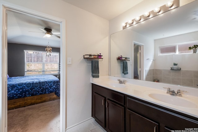 bathroom featuring a ceiling fan, ensuite bath, double vanity, and a sink