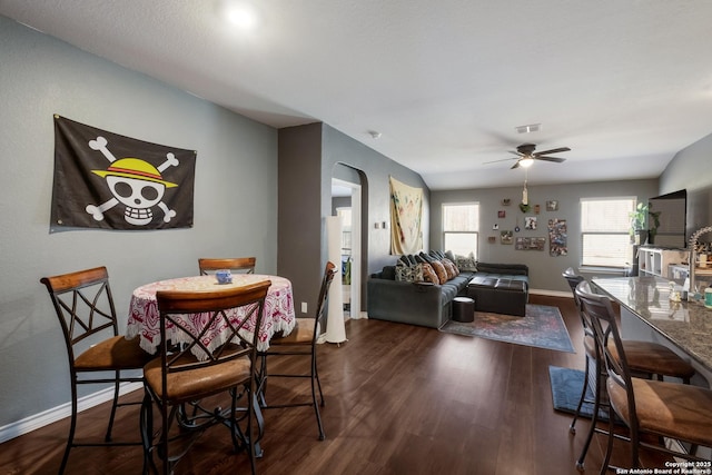 dining room featuring visible vents, ceiling fan, baseboards, arched walkways, and dark wood-style flooring