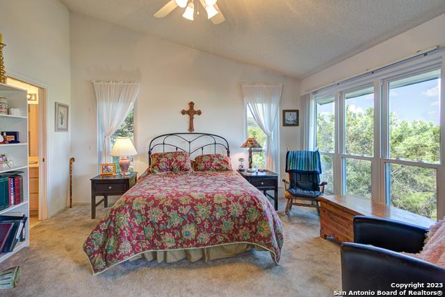 bedroom with lofted ceiling, a textured ceiling, carpet floors, and a ceiling fan