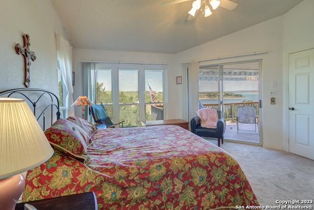 carpeted bedroom with vaulted ceiling, ceiling fan, and access to outside