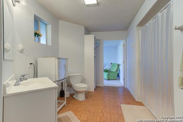 bathroom with toilet, vanity, and a textured ceiling