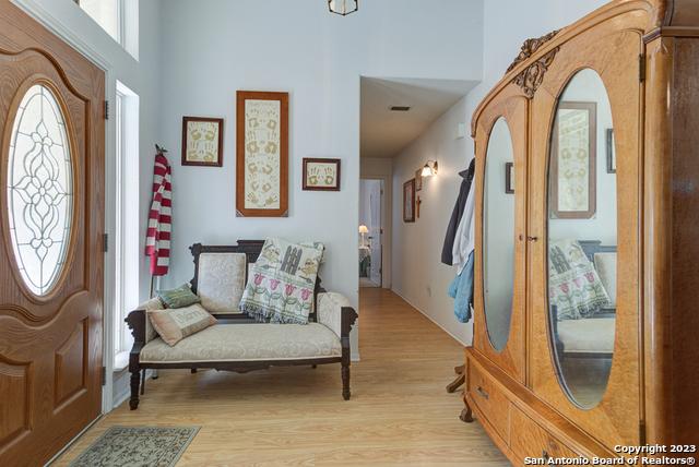 entryway featuring light wood finished floors, arched walkways, and a towering ceiling