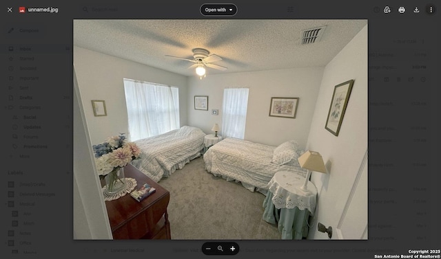 bedroom featuring visible vents, a textured ceiling, and a ceiling fan