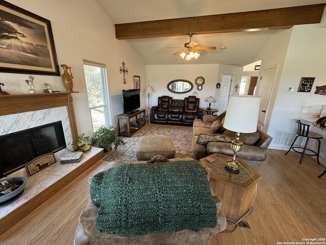 living room featuring a high end fireplace, beamed ceiling, high vaulted ceiling, and wood finished floors