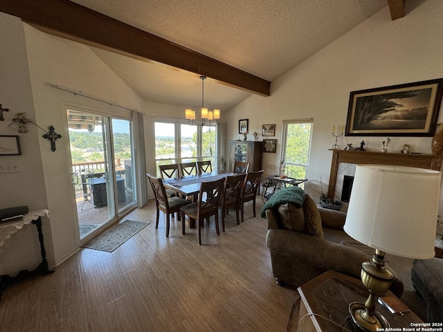 dining area with beam ceiling, a textured ceiling, wood finished floors, an inviting chandelier, and a fireplace